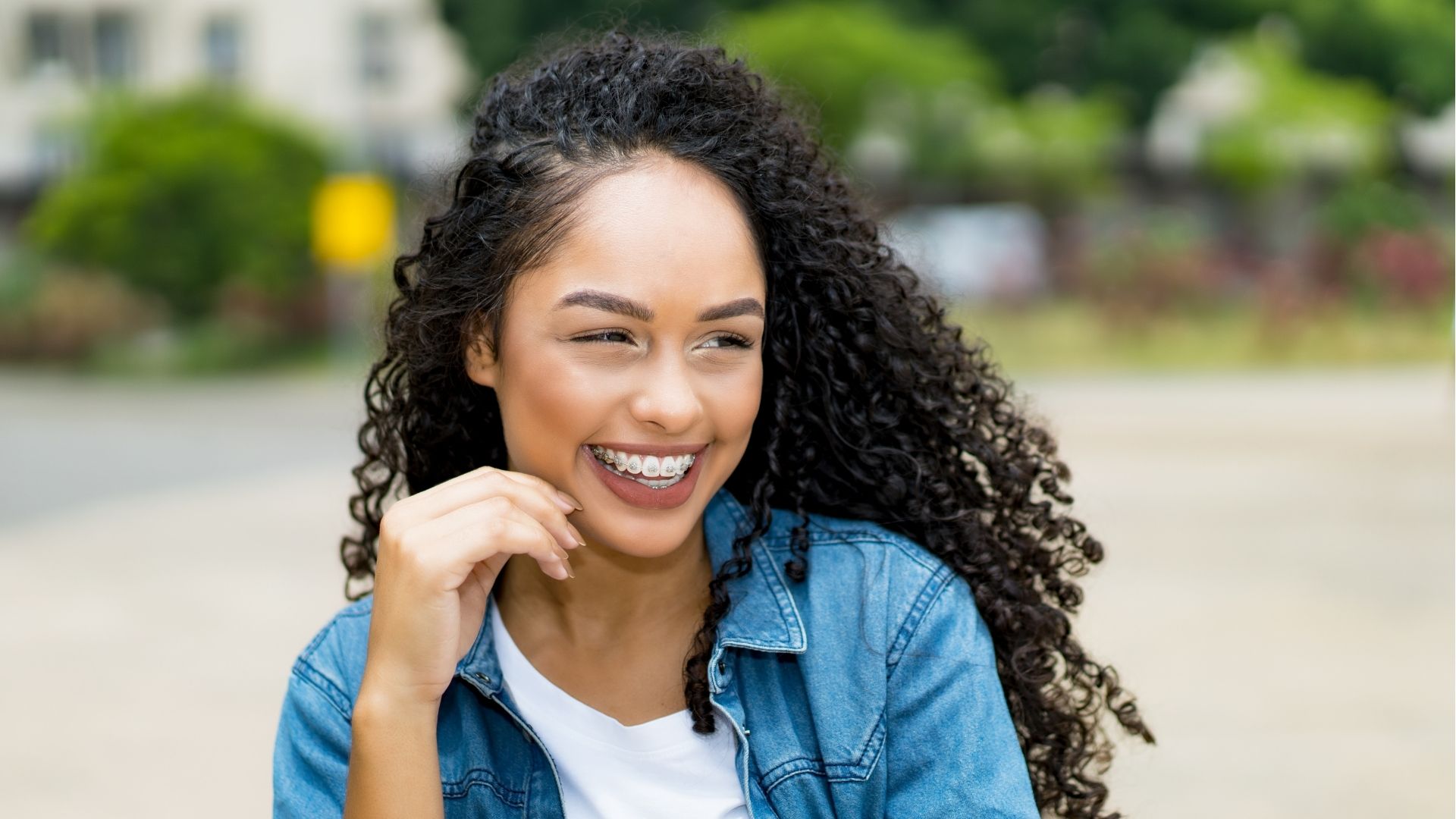 Smiling young adult with orthodontic braces on her teeth.