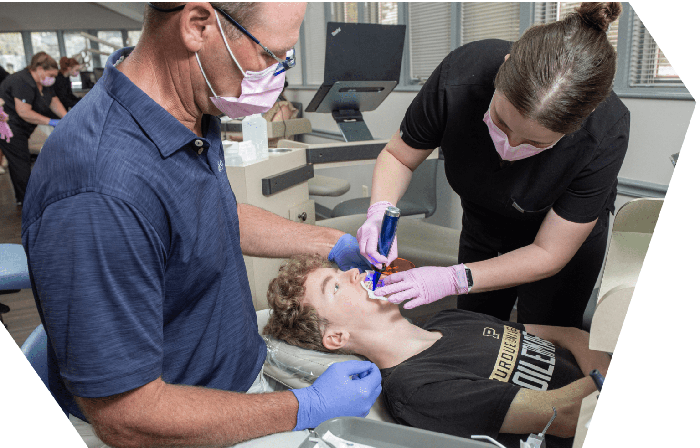Dr. Greg Werner and an assistant bonding braces for a teenage patient