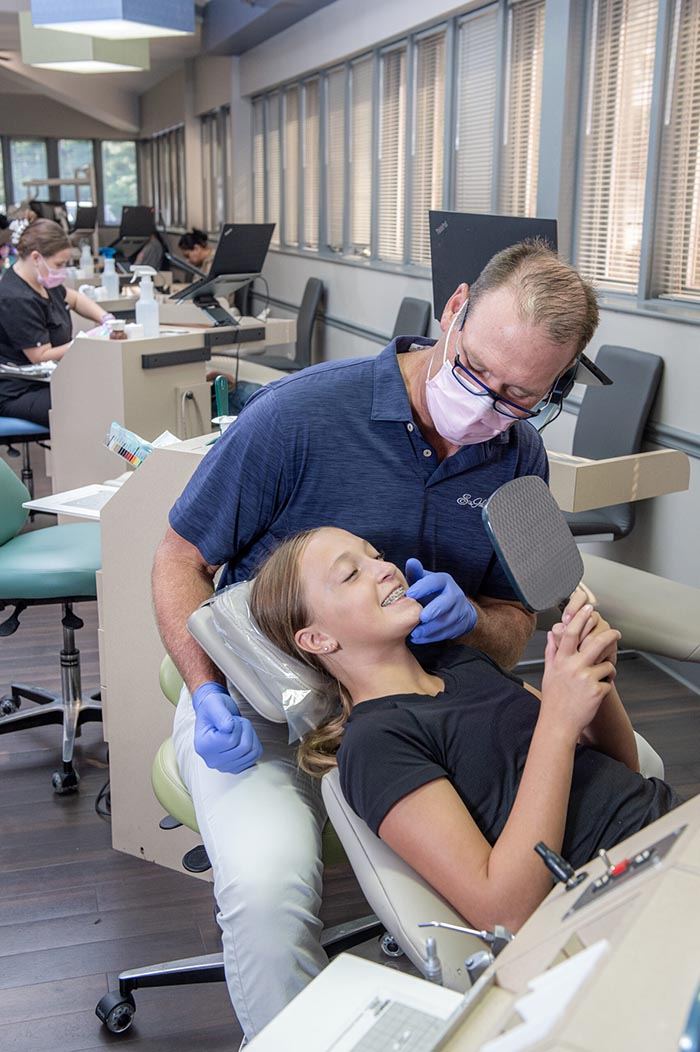 Dr. Greg Werner showing a teenage patient her new braces in a hand mirror